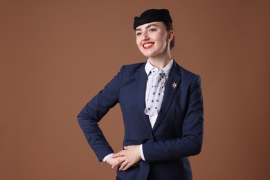 Photo of Charming stewardess in uniform on brown background