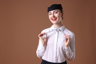 Photo of Charming stewardess in uniform on brown background. Space for text