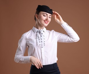 Photo of Charming stewardess in uniform on brown background