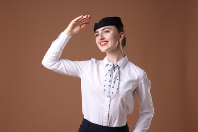 Photo of Charming stewardess in uniform on brown background
