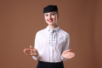 Photo of Positive stewardess doing pre-flight safety briefing on brown background