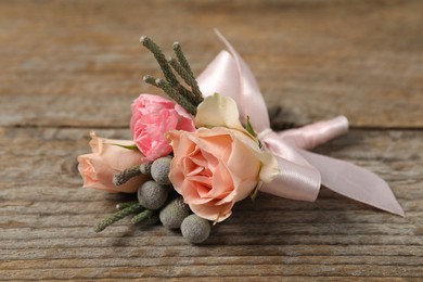 Photo of Boutonniere with beautiful flowers on wooden background, closeup