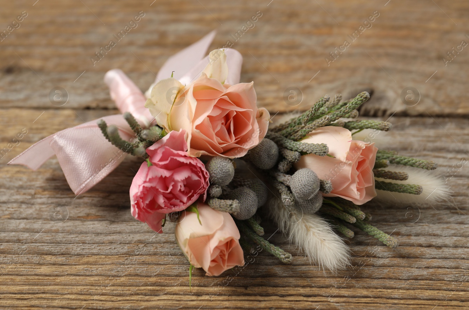 Photo of Boutonniere with beautiful flowers on wooden background, closeup