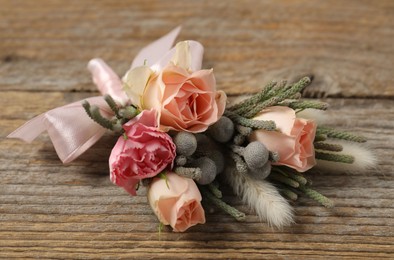 Photo of Boutonniere with beautiful flowers on wooden background, closeup