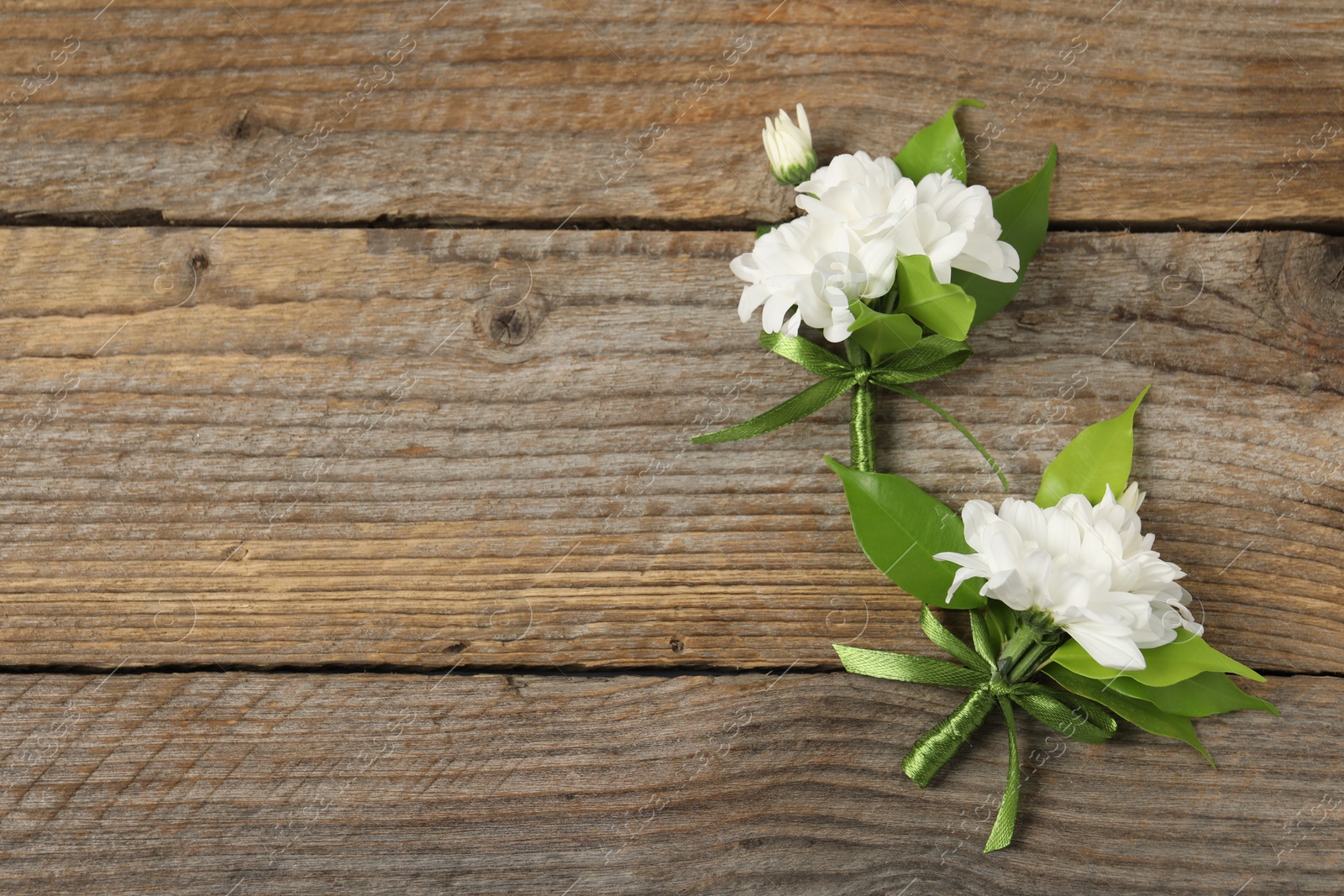 Photo of Boutonnieres with beautiful flowers on wooden background, flat lay. Space for text