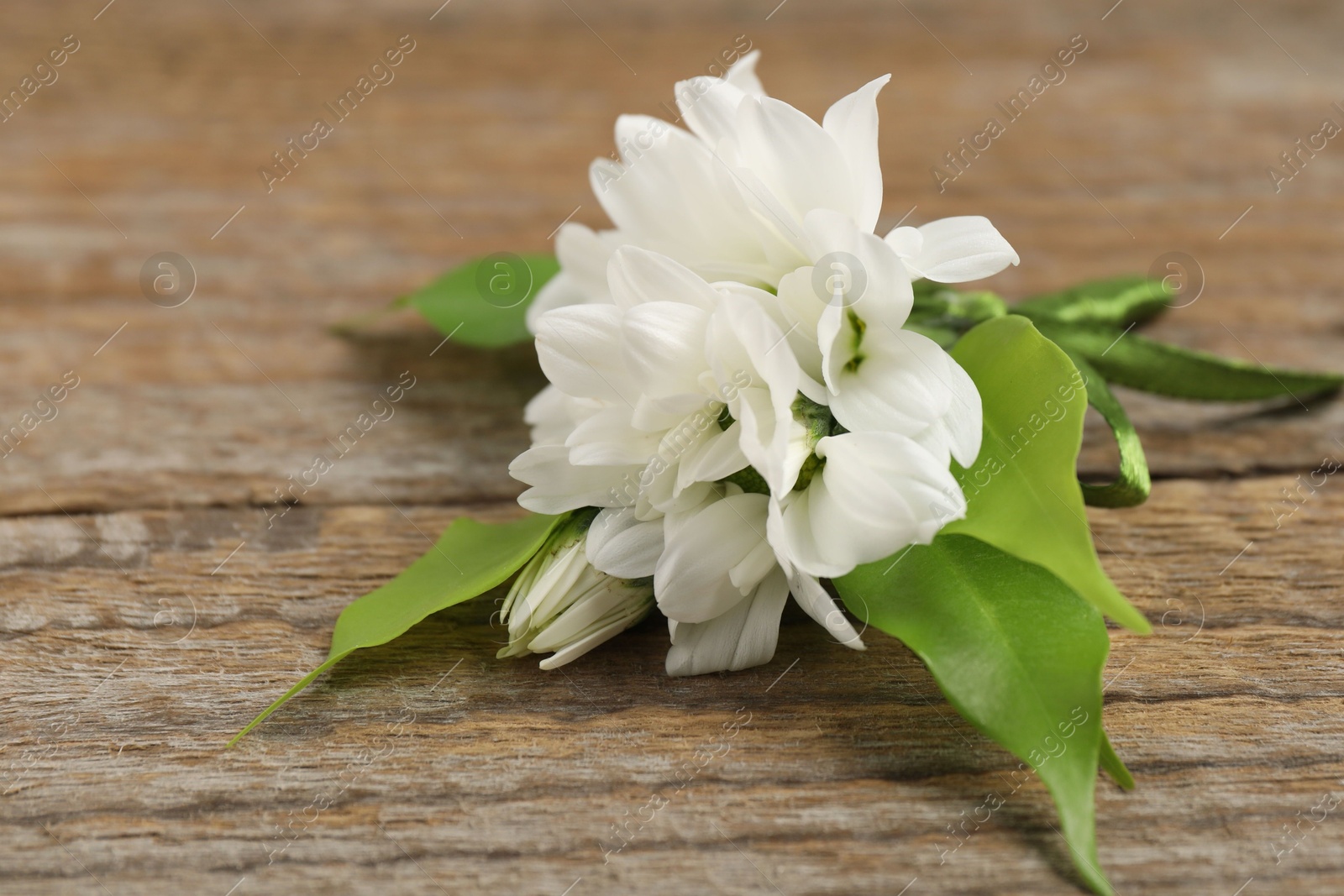 Photo of Boutonniere with beautiful flowers on wooden background, closeup