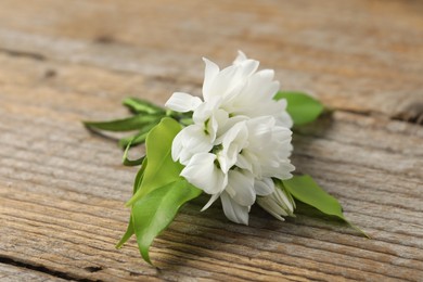 Photo of Boutonniere with beautiful flowers on wooden background, closeup