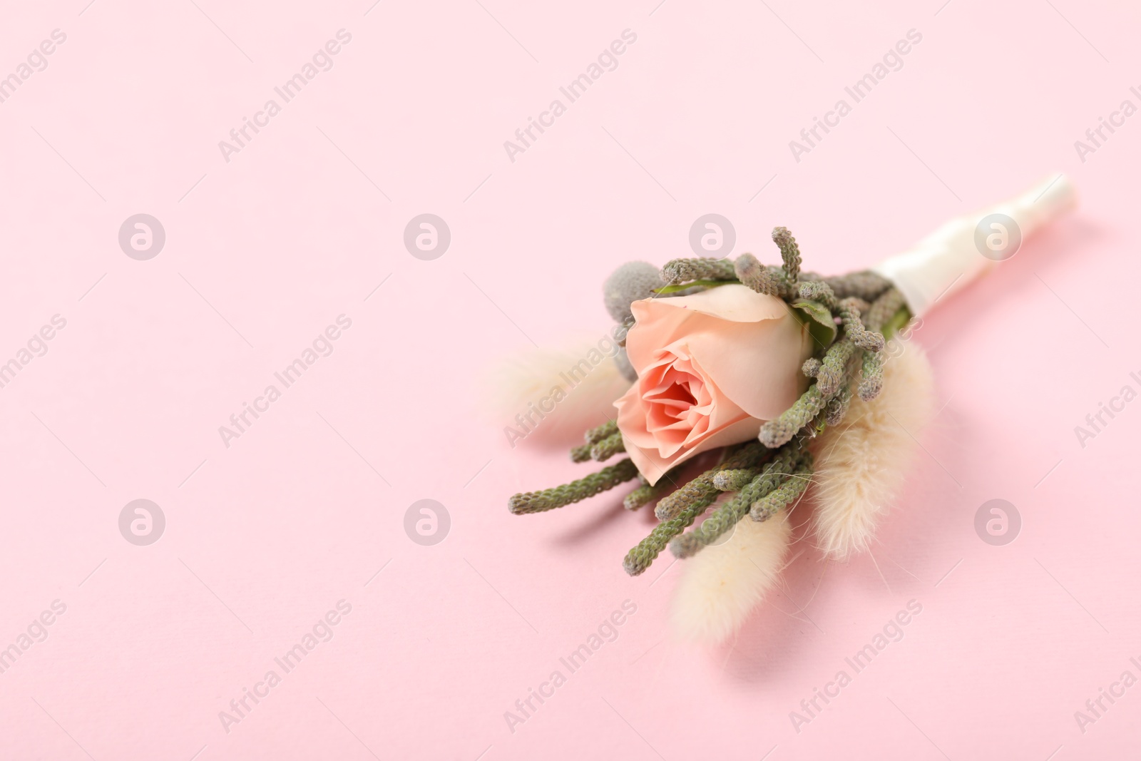 Photo of Boutonniere with beautiful flowers on light pink background, closeup. Space for text