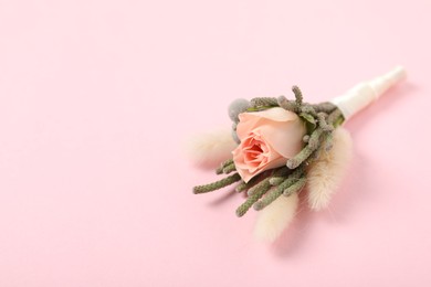 Photo of Boutonniere with beautiful flowers on light pink background, closeup. Space for text