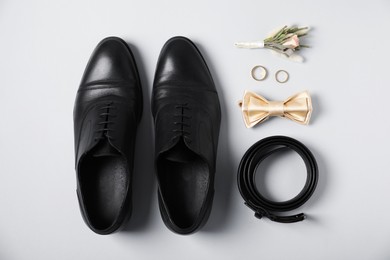 Photo of Flat lay composition with boutonniere, wedding rings and groom's accessories on white background