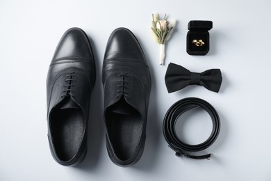 Photo of Flat lay composition with boutonniere, wedding rings and groom's accessories on white background