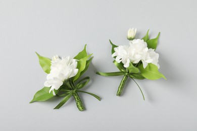 Photo of Boutonnieres with beautiful flowers on light background, flat lay