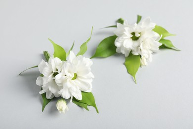 Photo of Boutonnieres with beautiful flowers on light background, closeup