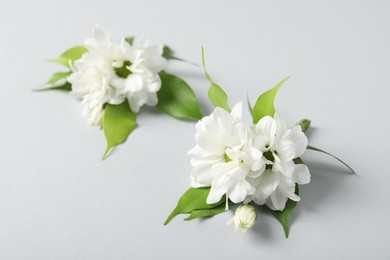 Photo of Boutonnieres with beautiful flowers on light background, closeup