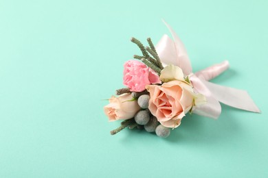 Photo of Boutonniere with beautiful flowers on turquoise background, closeup. Space for text