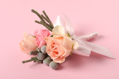 Photo of Boutonniere with beautiful flowers on light pink background, closeup