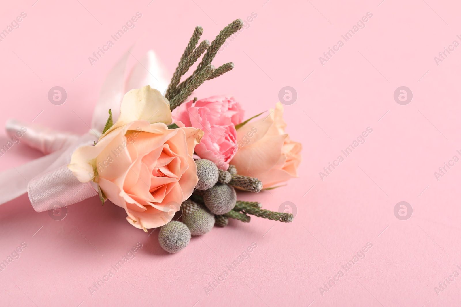 Photo of Boutonniere with beautiful flowers on light pink background, closeup. Space for text