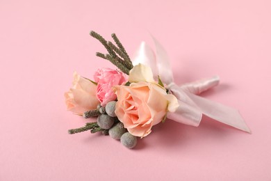 Photo of Boutonniere with beautiful flowers on light pink background, closeup