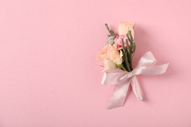 Photo of Boutonniere with beautiful flowers on light pink background, top view. Space for text