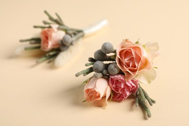 Photo of Boutonnieres with beautiful flowers on beige background, closeup