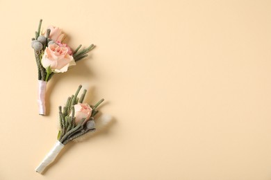 Photo of Boutonnieres with beautiful flowers on beige background, flat lay. Space for text