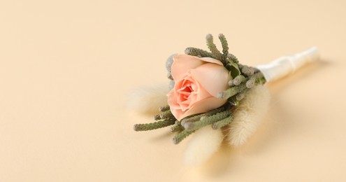 Photo of Boutonniere with beautiful flowers on beige background, closeup. Space for text