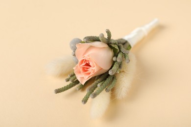 Photo of Boutonniere with beautiful flowers on beige background, closeup