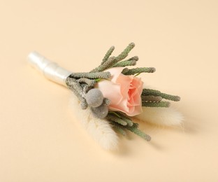 Photo of Boutonniere with beautiful flowers on beige background, closeup