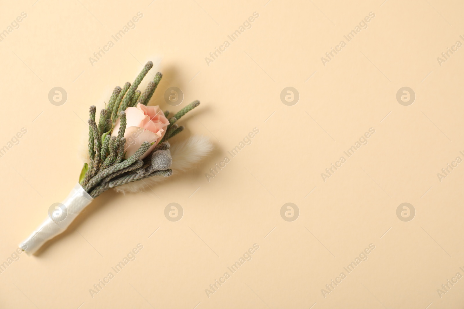 Photo of Boutonniere with beautiful flowers on beige background, top view. Space for text