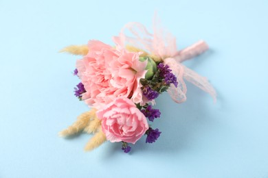 Photo of Boutonniere with beautiful flowers on light blue background. closeup