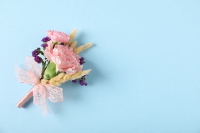 Photo of Boutonniere with beautiful flowers on light blue background, top view. Space for text