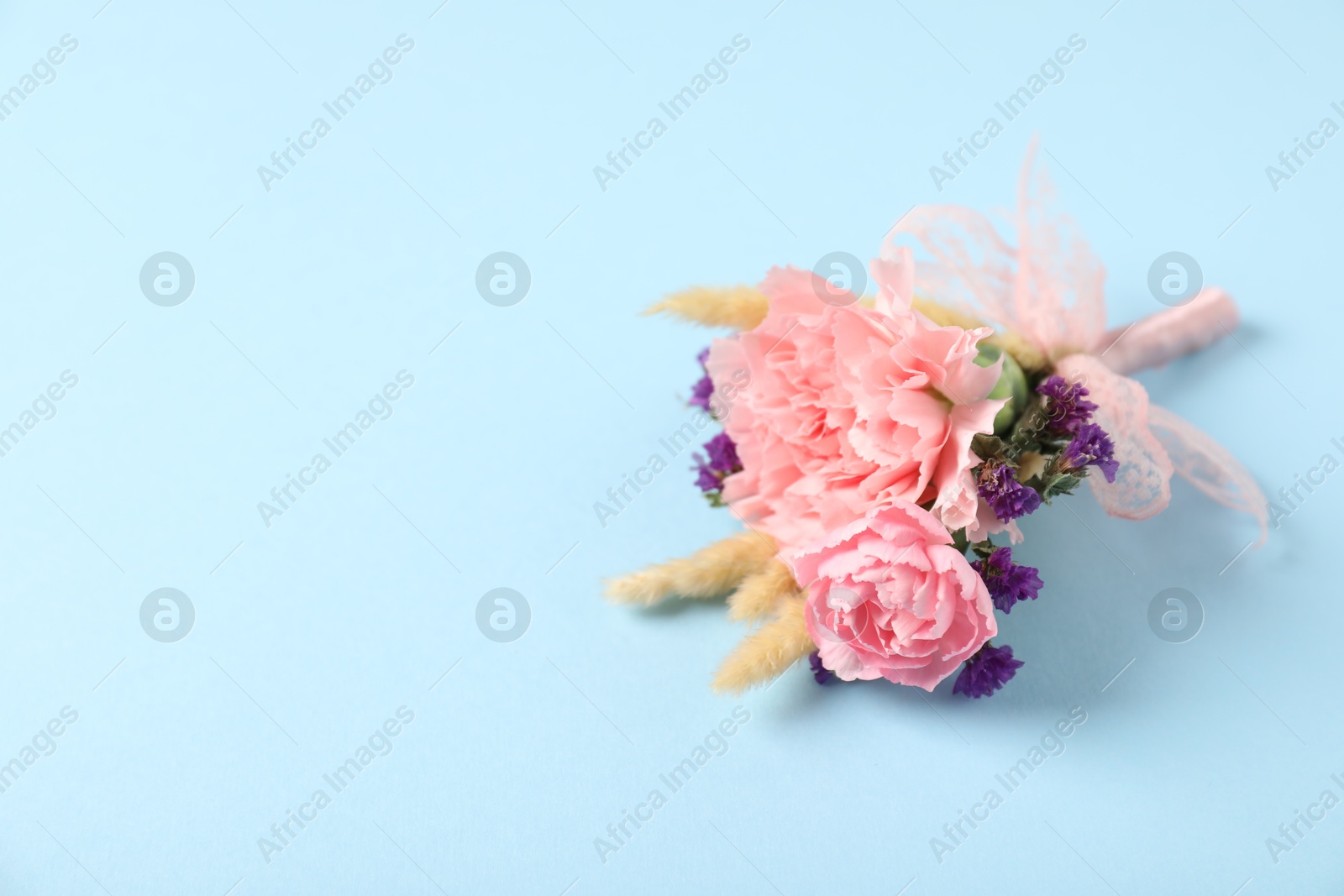 Photo of Boutonniere with beautiful flowers on light blue background. closeup. Space for text