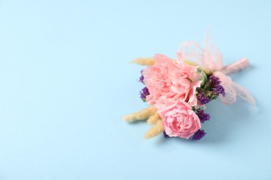 Photo of Boutonniere with beautiful flowers on light blue background. closeup. Space for text