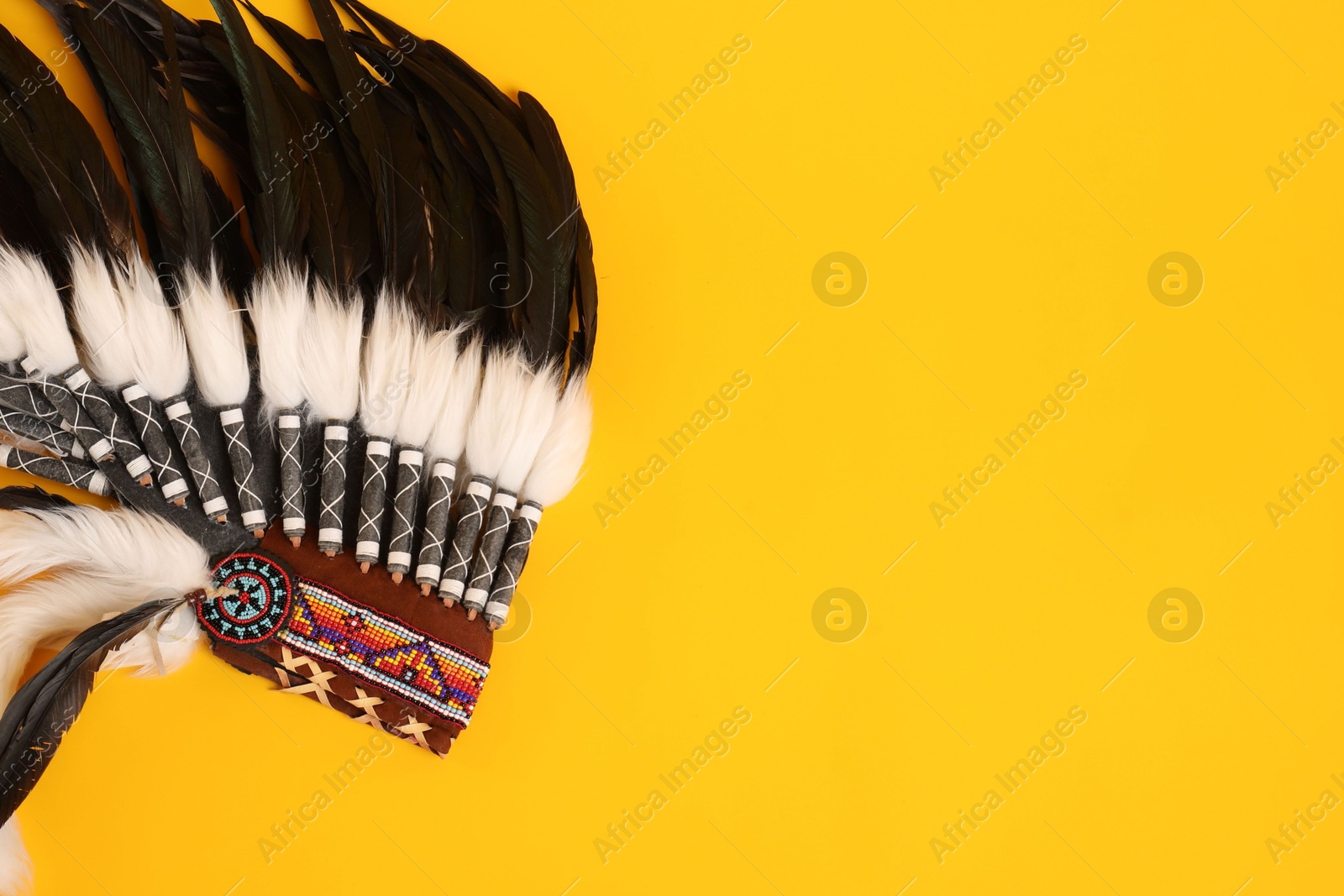 Photo of Traditional warbonnet (Native American chief headdress) on yellow background, top view