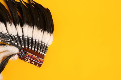 Photo of Traditional warbonnet (Native American chief headdress) on yellow background, top view