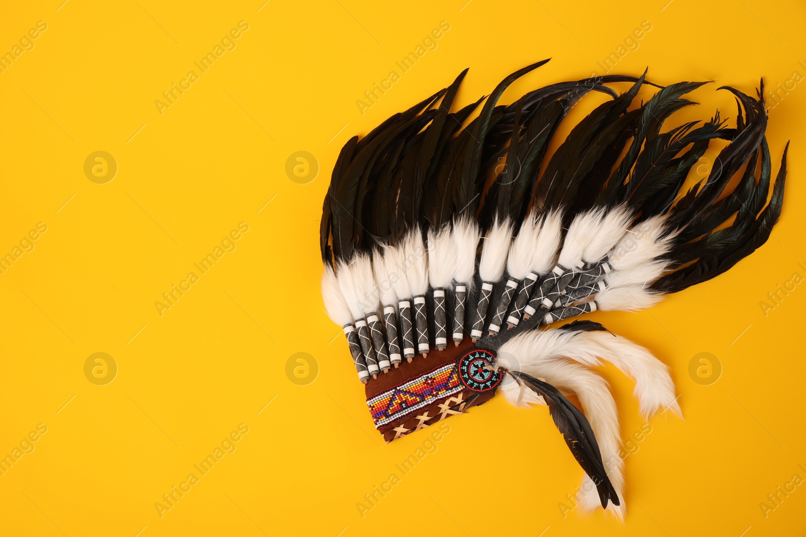 Photo of Traditional warbonnet (Native American chief headdress) on yellow background, top view