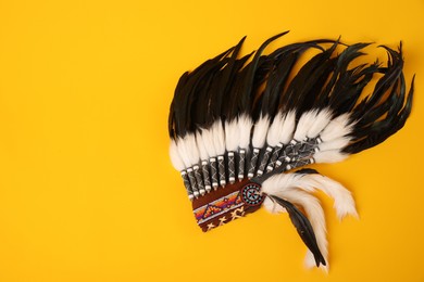 Photo of Traditional warbonnet (Native American chief headdress) on yellow background, top view
