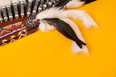 Photo of Traditional warbonnet (Native American chief headdress) on yellow background, closeup