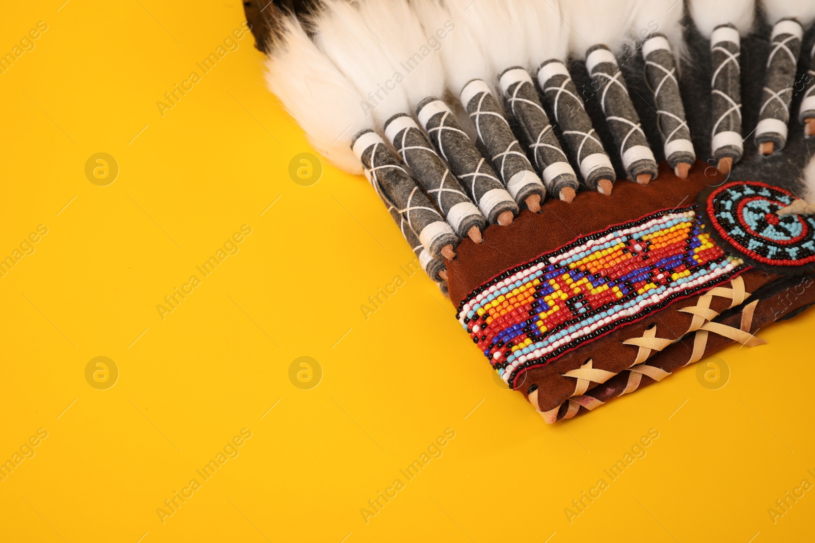Photo of Traditional warbonnet (Native American chief headdress) on yellow background, closeup
