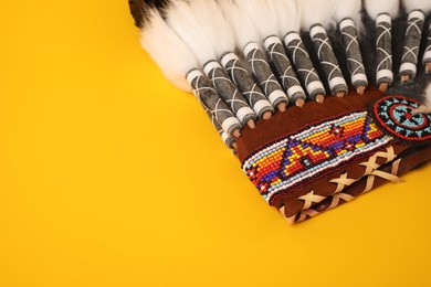 Photo of Traditional warbonnet (Native American chief headdress) on yellow background, closeup