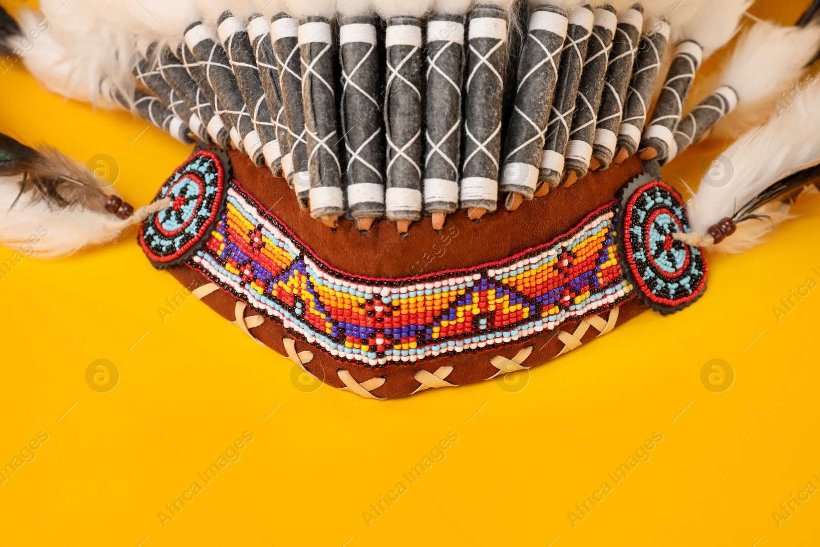 Photo of Traditional warbonnet (Native American chief headdress) on yellow background, closeup