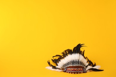 Photo of Traditional warbonnet (Native American chief headdress) on yellow background. Space for text
