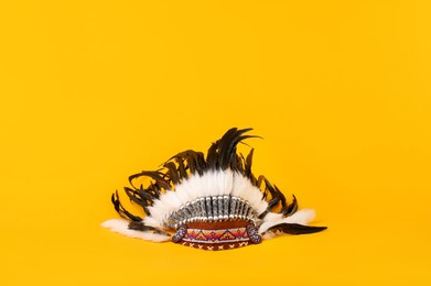 Photo of Traditional warbonnet (Native American chief headdress) on yellow background. Space for text
