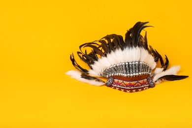 Photo of Traditional warbonnet (Native American chief headdress) on yellow background. Space for text