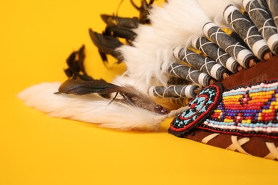 Photo of Traditional warbonnet (Native American chief headdress) on yellow background, closeup