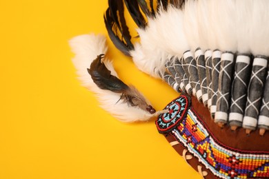 Photo of Traditional warbonnet (Native American chief headdress) on yellow background, closeup