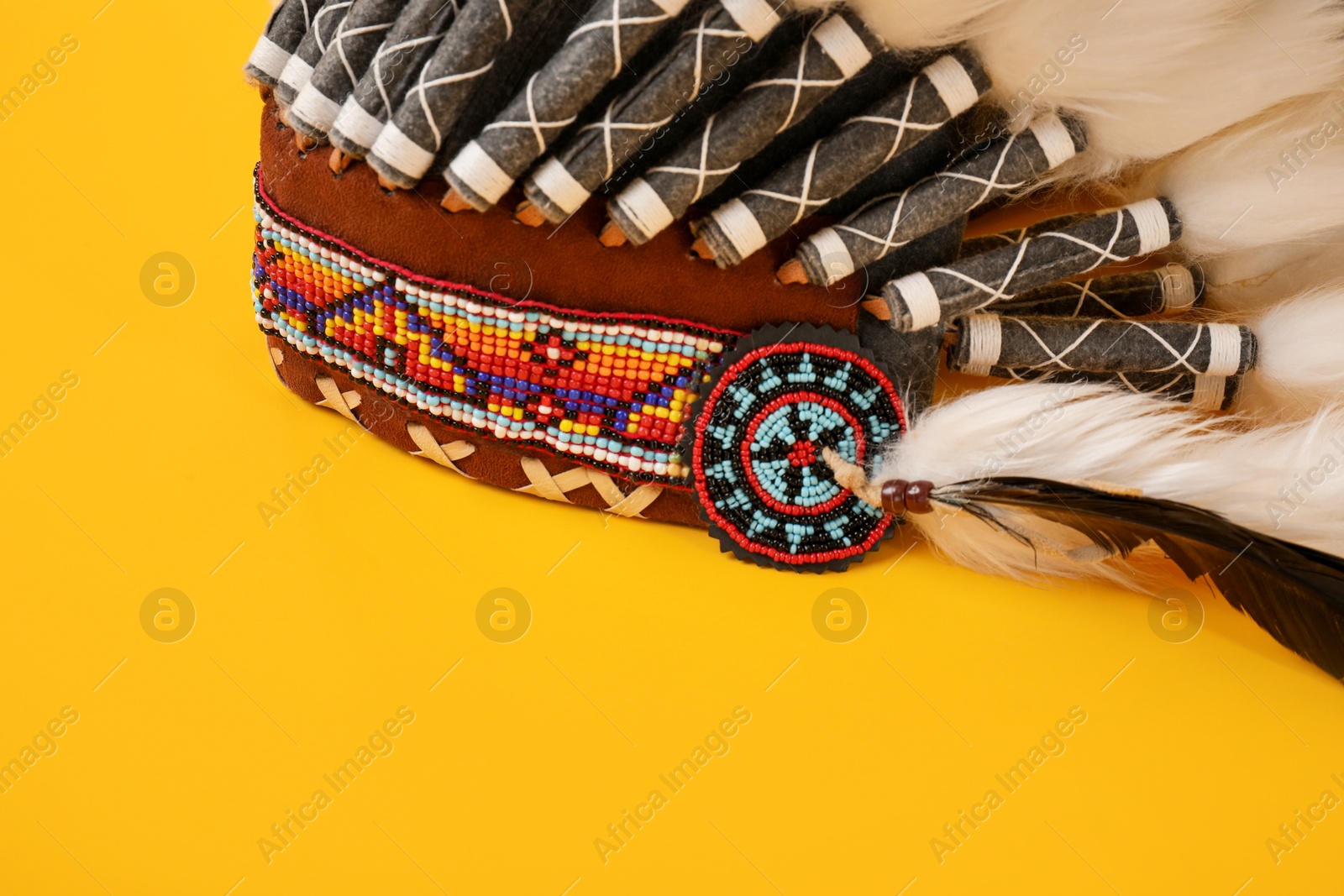 Photo of Traditional warbonnet (Native American chief headdress) on yellow background, closeup