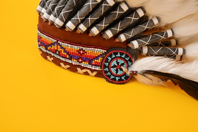Photo of Traditional warbonnet (Native American chief headdress) on yellow background, closeup
