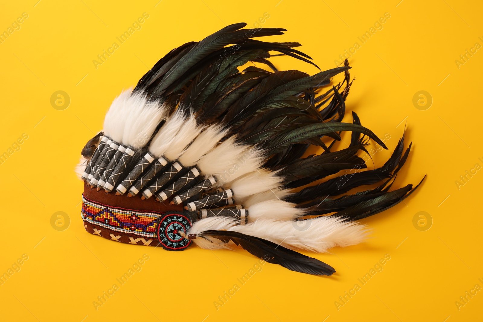Traditional warbonnet (Native American chief headdress) on yellow background Photo of Traditional warbonnet (Native American chief headdress) on yellow background