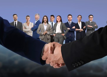 Image of Partners shaking hands against group of business people